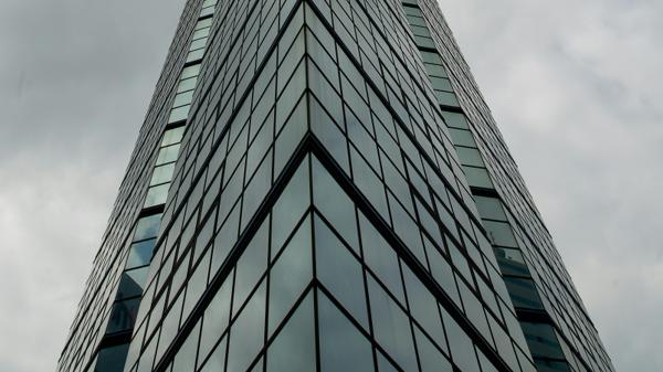 Immeuble en verre vu en contre-plongée sous un ciel nuageux dramatique