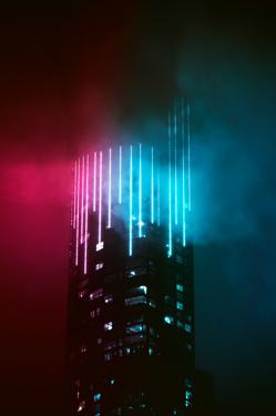 Sommet de tour illuminé de lignes turquoise et rouge dans la nuit